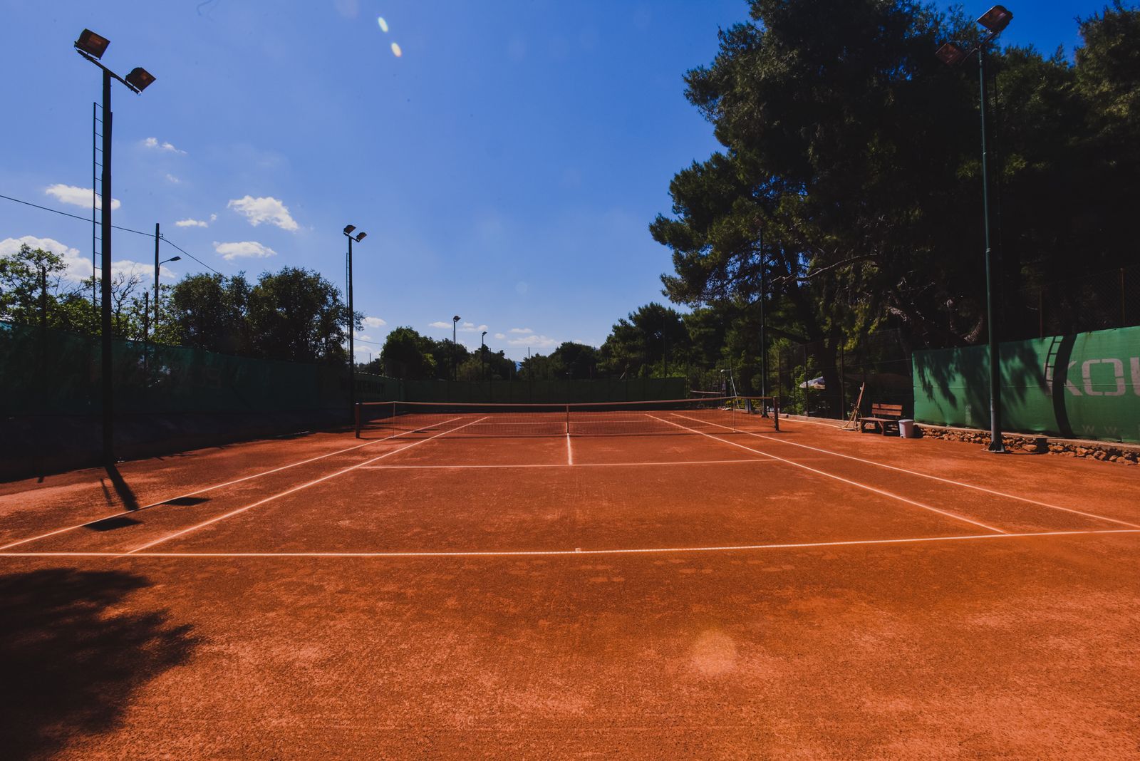 Wide view of the clay court under blue sky
